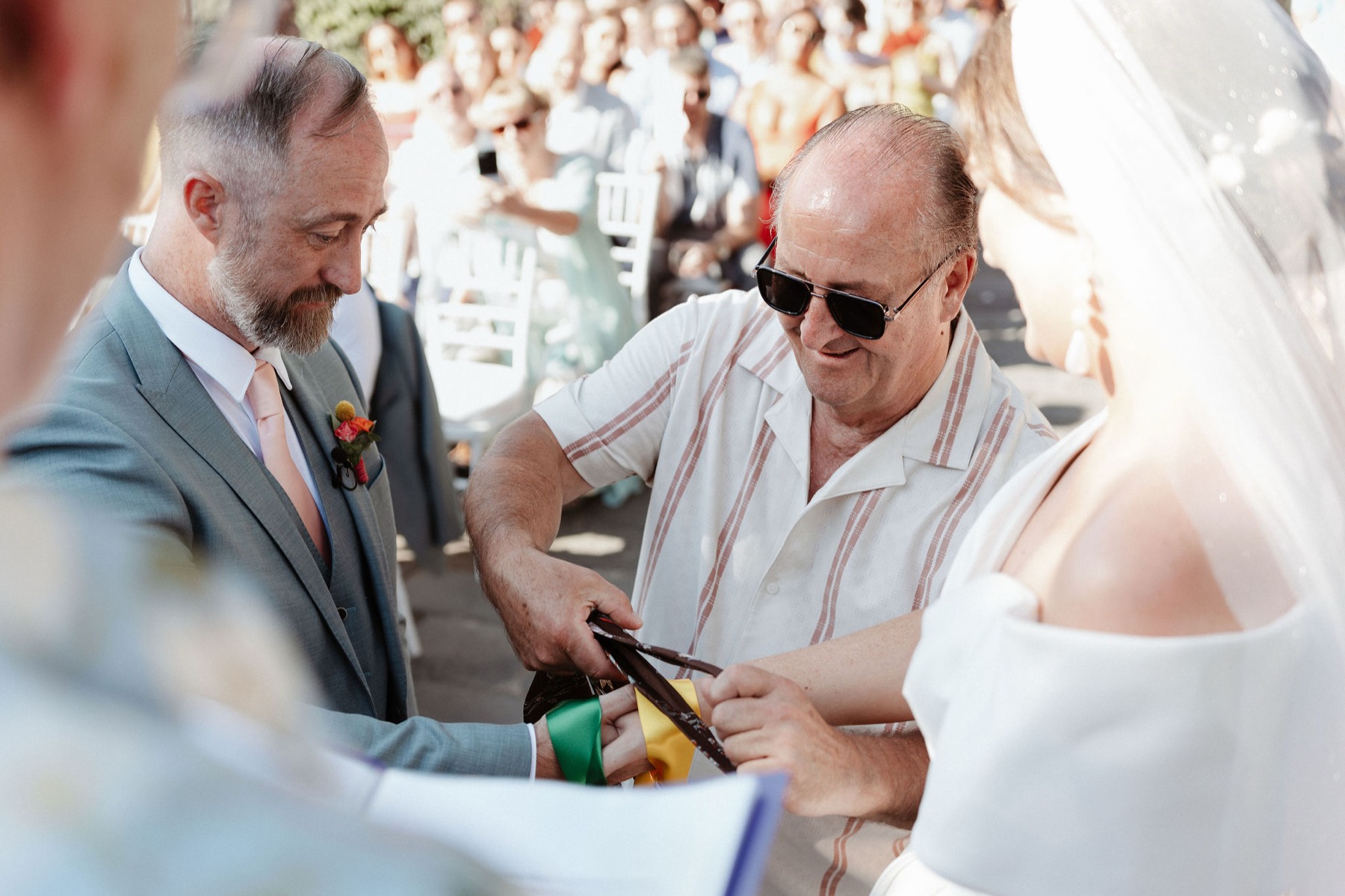 The handfasting, the couple's hands tied with coloured ribbon