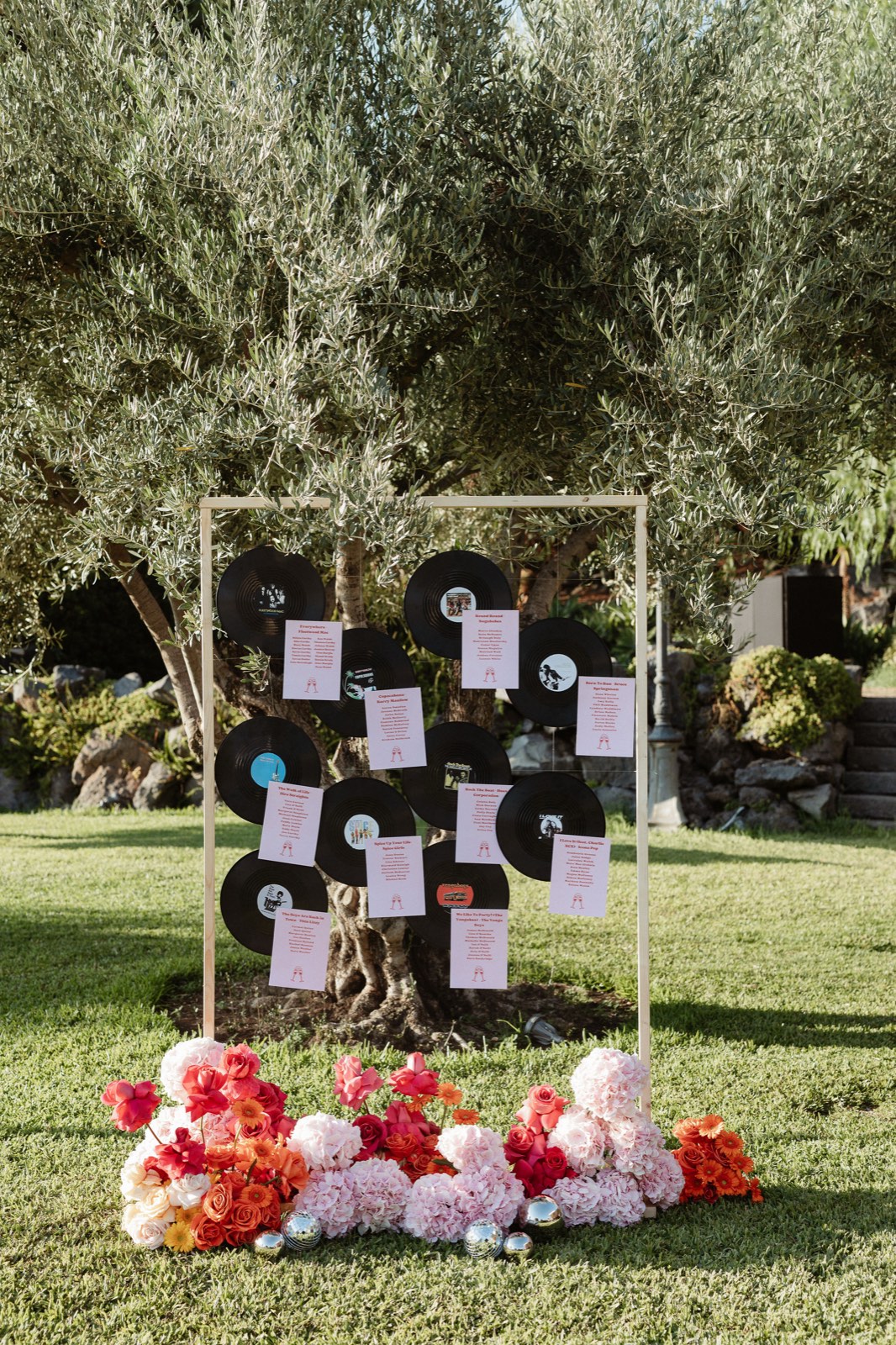 The seating chart pinned to vinyl records, hanging from an olive tree