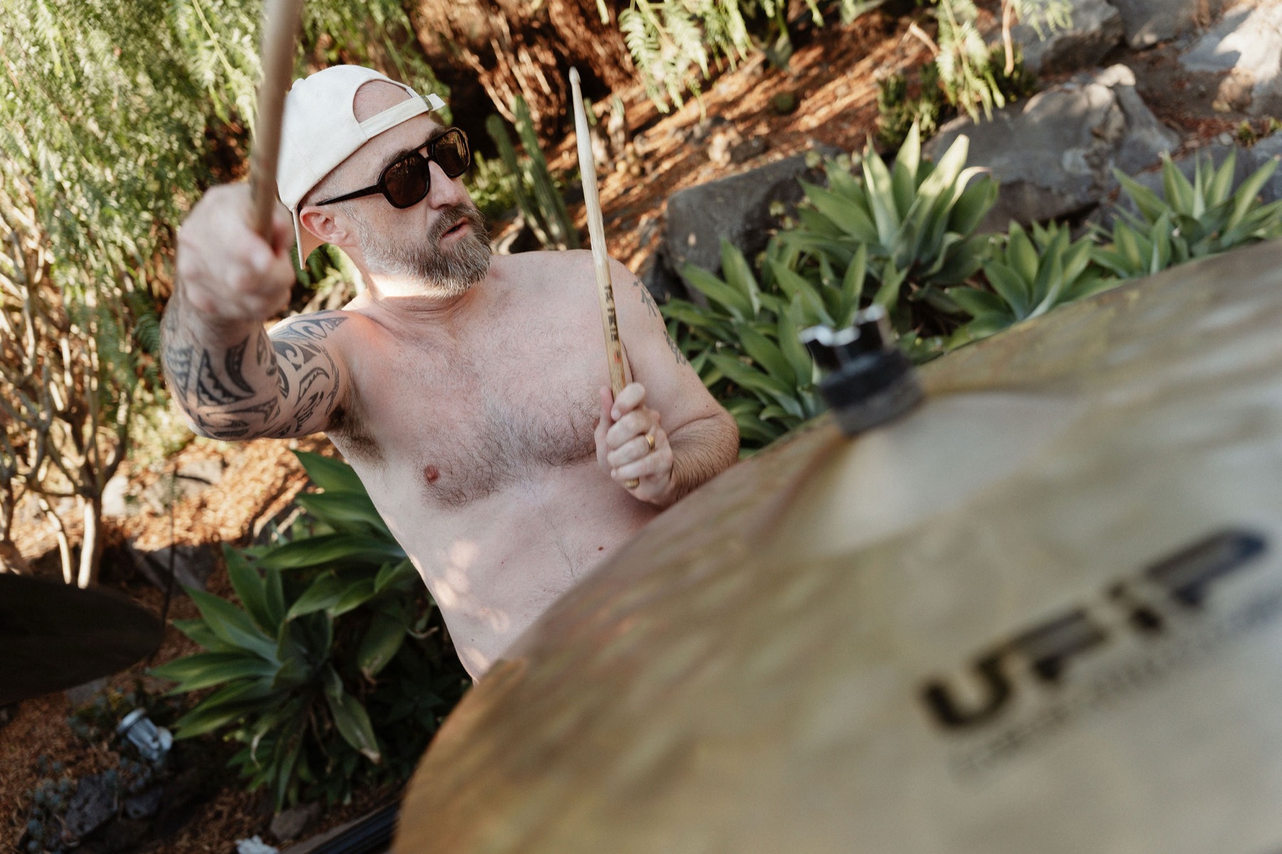 Ken at the drums by the pool, sticks raised